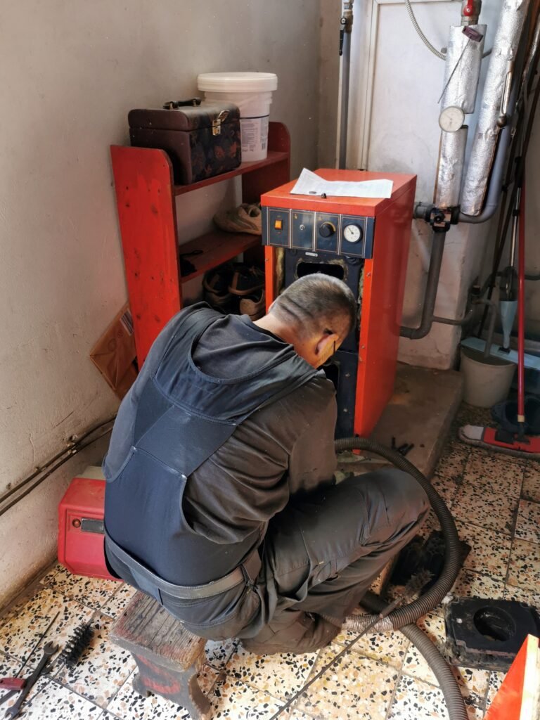 Rear view of professional chimney sweep cleaning central heating furnace.